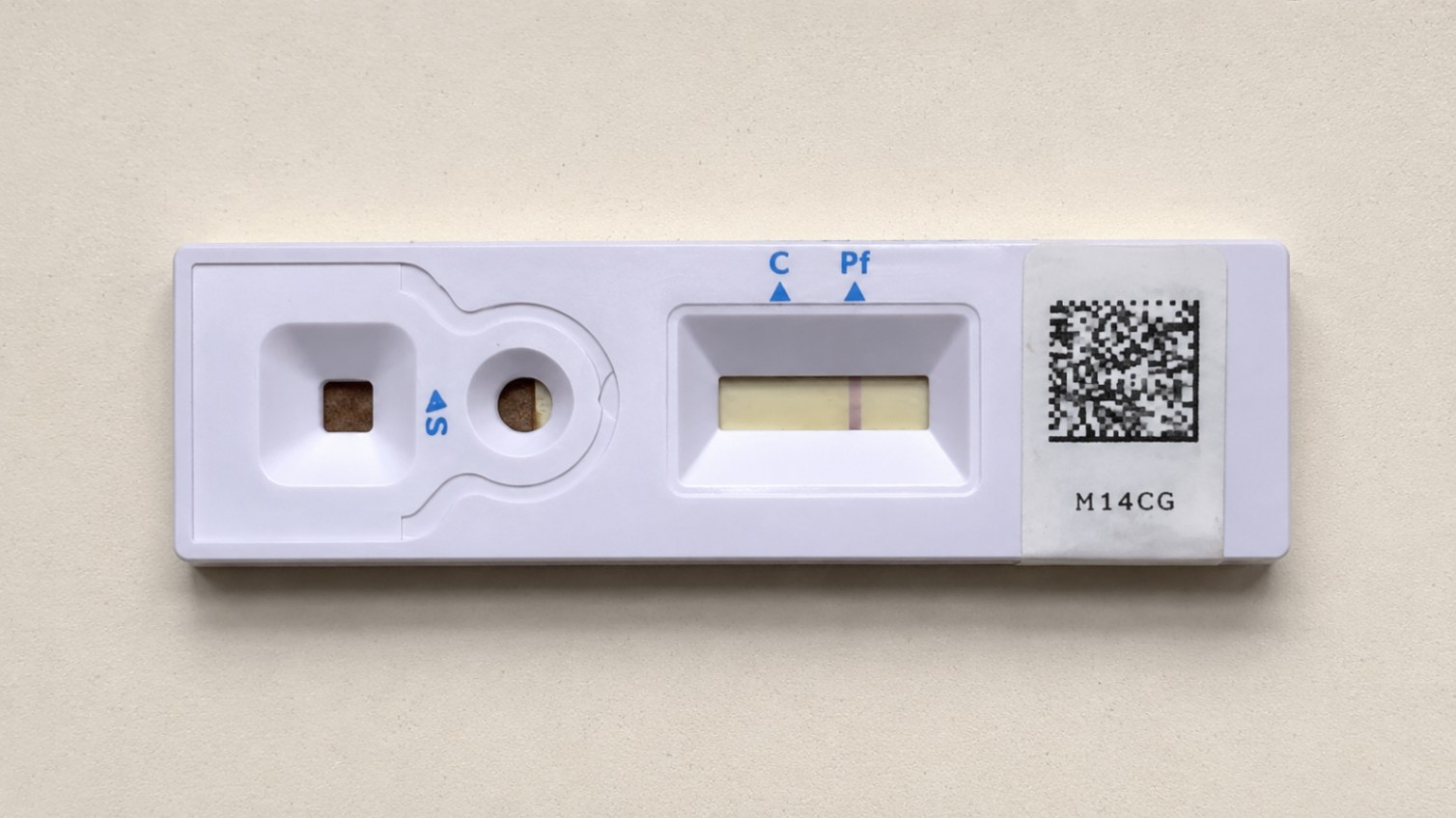 Close-up of a malaria rapid-test cassette being photographed with a smartphone on a clean counter.